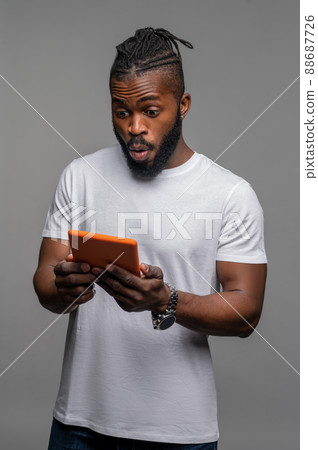 Shocked guy staring at the gadget in his hands 88687726