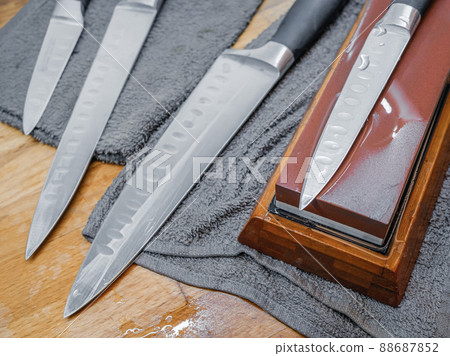 Selective focus on the blade of a steel kitchen knife lying on a water whetstone Selective focus on the blade of a steel kitchen knife lying on a water whetstone 88687852