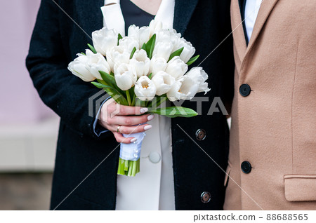 A bouquet of white tulips in the hands of the bride A bouquet of white tulips in the hands of the bride 88688565