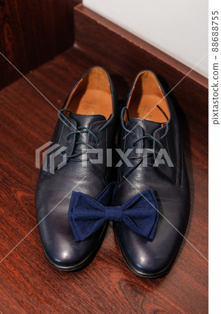 Blue bow tie on blue classic shoes on brown background Blue bow tie on blue classic shoes on brown background 88688755