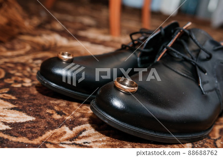 Gold wedding rings on black shoes on the floor. Accessories for the groom on the wedding day 88688762