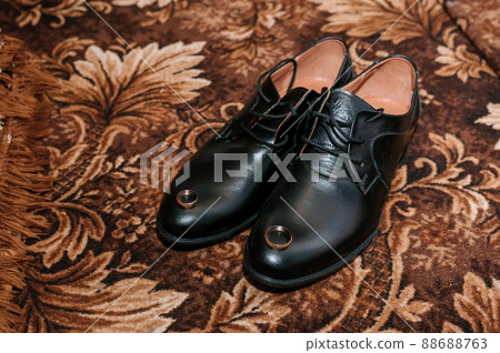 Gold wedding rings on black shoes on the floor. Accessories for the groom on the wedding day 88688763