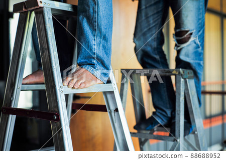 Selective focus on the aluminum ladder with defocused feet of workers working on it 88688952