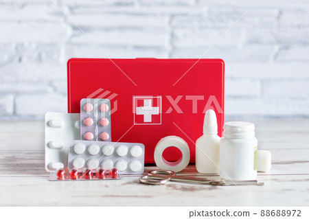 First aid kit red box with medical equipment and medications for emergency on white wooden background. 88688972