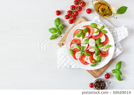 Caprese salad with mozzarela, tomatoes, fresh olive oil and basil on white background top view. Caprese salad with mozzarela, tomatoes, fresh olive oil and basil on white background top view. 88689019