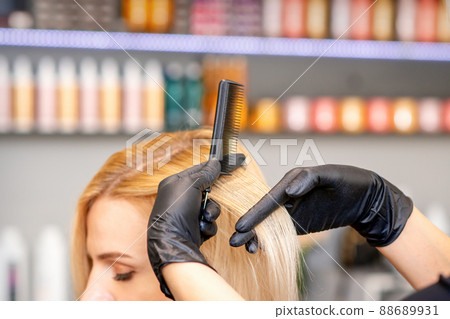 Beautiful young blonde woman with long straight blonde hair getting a haircut at the hairdresser salon Beautiful young blonde woman with long straight blonde hair getting a haircut at the hairdresser salon 88689931