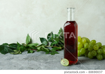 Bottle of vinegar, grape and leaves on gray textured table Bottle of vinegar, grape and leaves on gray textured table 88690037
