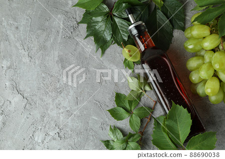 Bottle of vinegar, grape and leaves on gray textured table 88690038