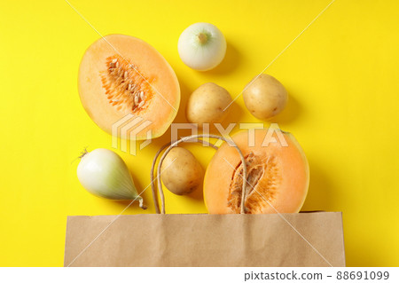Paper bag with potato, onion and melon on yellow background 88691099