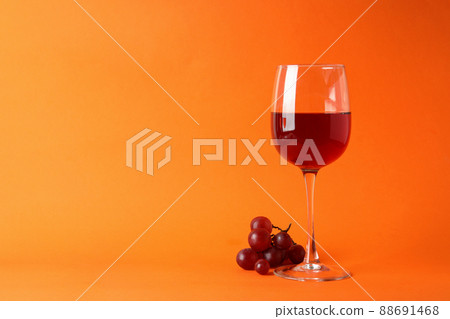 Glasses of red wine and grape on orange background Glasses of red wine and grape on orange background 88691468