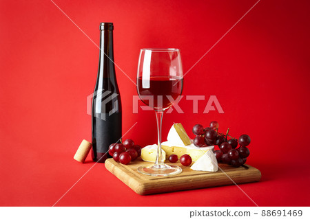 Board with wine, cheese and grape on red background Board with wine, cheese and grape on red background 88691469