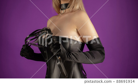 Beautiful young woman in a leather corset posing with a whip in her hands Beautiful young woman in a leather corset posing with a whip in her hands 88691914