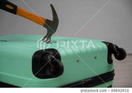 A woman hits a suitcase with a hammer on a white background. A woman hits a suitcase with a hammer on a white background. 88692658