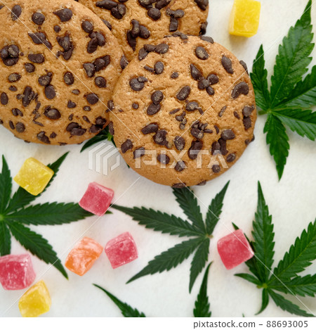 American cookies with cannabis extract. Sweets with CBD oil. Marijuana leaves on white background American cookies with cannabis extract. Sweets with CBD oil. Marijuana leaves on white background 88693005