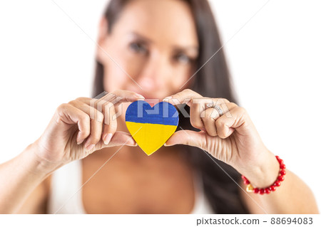 Young activist holding a heart in Ukraine colours representing love and empathy to attacked people. Isolated background 88694083