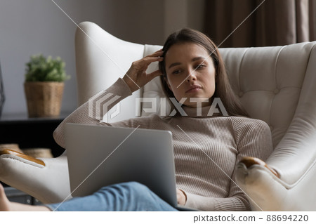 Pensive serious millennial woman reading text, watching content on laptop Pensive serious millennial woman reading text, watching content on laptop 88694220