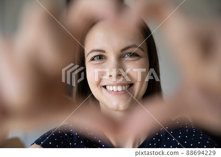 Woman showing heart shape to camera, close up 88694229