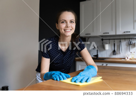 Woman wear gloves cleaning kitchen counter smile look at camera Woman wear gloves cleaning kitchen counter smile look at camera 88694333