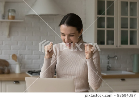 Cheerful excited girl looking at display with winner yes hands Cheerful excited girl looking at display with winner yes hands 88694387