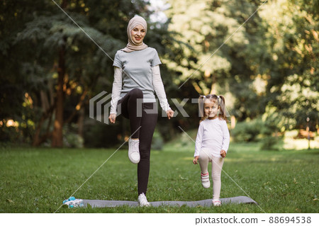 Muslim mother and her daughter, having workout in the park, doing high stepping exercise Muslim mother and her daughter, having workout in the park, doing high stepping exercise 88694538