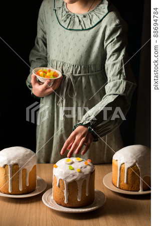 Girl decorates Easter cakes with candied fruit 88694784