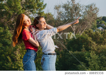 Friendship, meeting, togetherness, greetings, gathering of friends. Group of girls friends cheering and waving their hands to their friends in summer park. 88695338