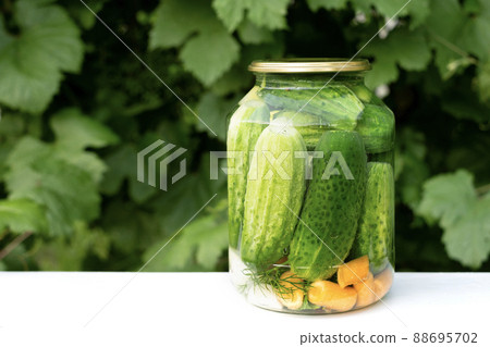 A canned jar with cucumbers and carrots is on the table in the garden. Preparation and preservation of vegetables in marinade. Harvesting and storage A canned jar with cucumbers and carrots is on the table in the garden. Preparation and preservation of vegetables in marinade. Harvesting and storage 88695702