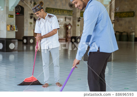 muslim male cleaning the mosque using broom and sweeping the floor 88696593