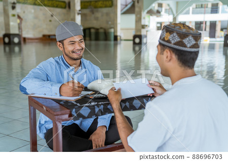 muslim man giving zakat charity for eid mubarak at the mosque muslim man giving zakat charity for eid mubarak at the mosque 88696703
