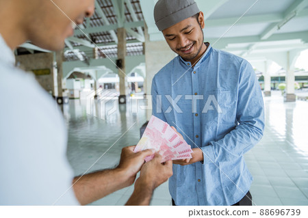 muslim paying some zakat charity using cash at the mosque 88696739