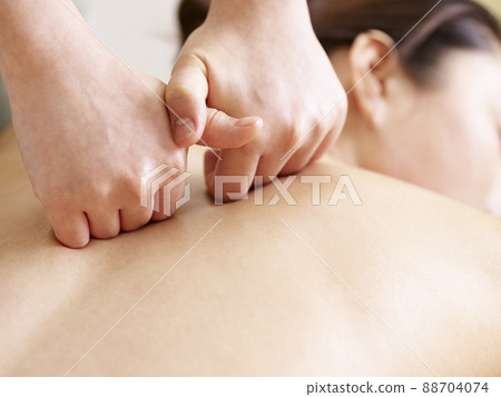 close-up of hands of a masseur massaging back of a young asian woman close-up of hands of a masseur massaging back of a young asian woman 88704074
