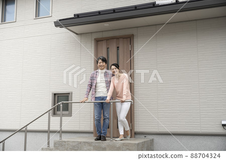 A middle-aged couple standing in front of the front door of their house 88704324