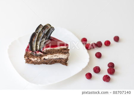 A piece of chocolate cake with cherries. Cake side view on a white background. Copy space 88707140