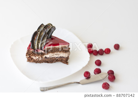 A piece of chocolate cake with cherries. Cake side view on a white background. Copy space 88707142