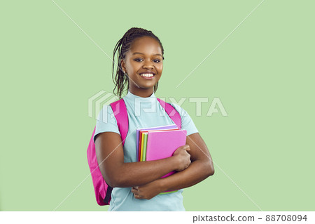 Smiling dark skinned female student with backpack and textbooks on light green background. Smiling dark skinned female student with backpack and textbooks on light green background. 88708094