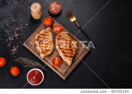 Delicious fresh grilled chicken fillet with spices and herbs on a dark concrete background 88708264
