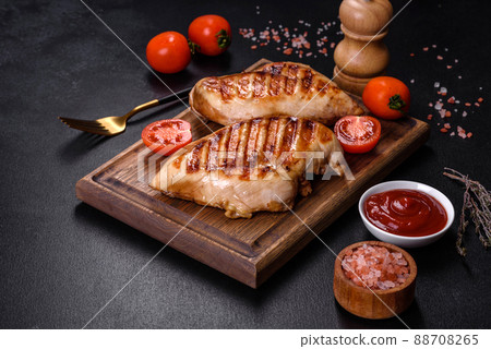 Delicious fresh grilled chicken fillet with spices and herbs on a dark concrete background 88708265
