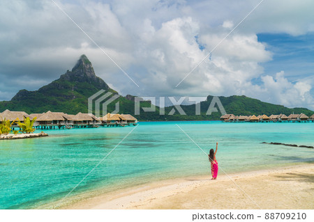 Polynesian hula dancer dancing on Bora Bora beach at luxury overwater bungalows hotel resort at luau show party for tourists. Tahiti, French Polynesia 88709210