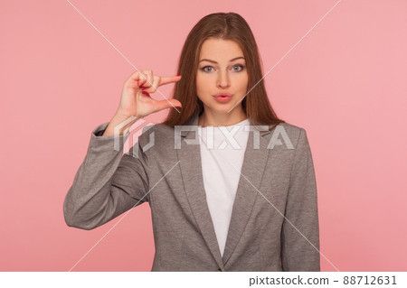 Need some more. Portrait of sceptic displeased young woman in business suit making a little bit gesture, small size, dissatisfied with low rating. indoor studio shot isolated on pink background Need some more. Portrait of sceptic displeased young woman in business suit making a little bit gesture, small size, dissatisfied with low rating. indoor studio shot isolated on pink background 88712631