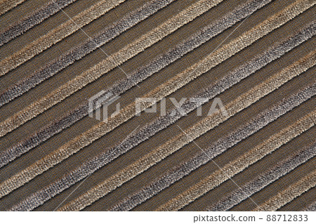 The texture of a natural beige cotton corduroy fabric with light stripes, located diagonally. The ridges of the corduroy on the diagonal 88712833