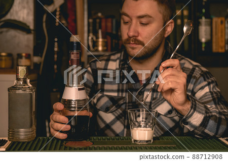 Focused bartender preparing alcoholic cocktail White Russian behind bar counter Focused bartender preparing alcoholic cocktail White Russian behind bar counter 88712908