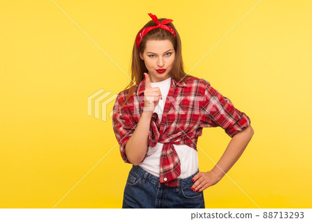 I told you. Portrait of strict pinup girl in checkered shirt and headband teaching with admonishing gesture, warning looking bossy, dispraise concept. retro 50's style, studio shot, yellow background 88713293