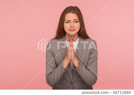 Please, I need help. Portrait of imploring young woman in business suit praying, begging with naughty and pleading grimace, gesture of asking apologizing. studio shot isolated on pink background 88713860