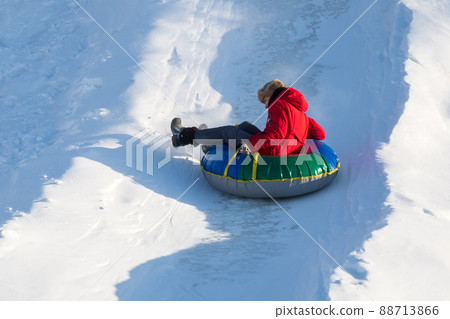 Girl riding on snow tube, during tubing in winter park. Winter season, selective focus Girl riding on snow tube, during tubing in winter park. Winter season, selective focus 88713866