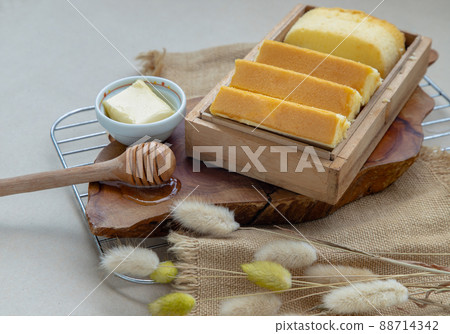 Slices of four butter cakes in wooden box served with butter and honey. 88714342