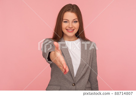 Hello, nice to meet you. Portrait of woman in business suit giving hand to handshake and smiling friendly, consultant or HR manager offering job, partnership. studio shot isolated on pink background 88714807