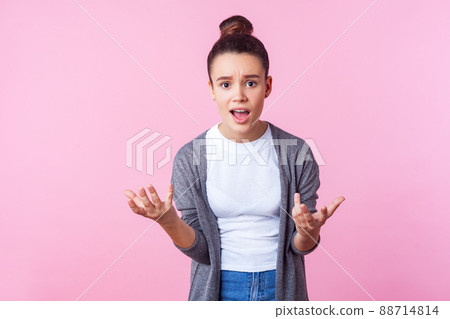 How could you. Portrait of brunette teen girl with bun hairstyle in casual clothes raising hands asking why, looking indignant displeased, making claims. indoor studio shot isolated on pink background How could you. Portrait of brunette teen girl with bun hairstyle in casual clothes raising hands asking why, looking indignant displeased, making claims. indoor studio shot isolated on pink background 88714814