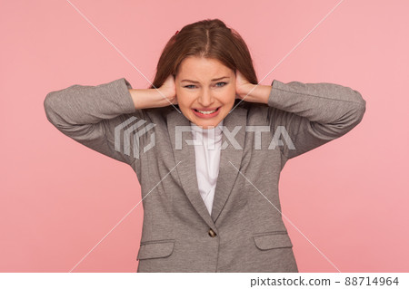 Don't want to listen. Portrait of irritated stressed out young woman in business suit tightly covering ears and looking with desperate annoyed expression, hearing voices, nervous breakdown. isolated 88714964