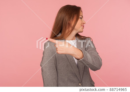 Get out. Portrait of irritated young woman in business suit pointing to side, ordering to leave her alone, looking resentful annoyed, lady boss firing from work. indoor studio shot, pink background 88714965