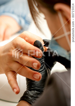 Manicure painting process. Manicure master paint the nails with transparent varnish in a nail salon, close up Manicure painting process. Manicure master paint the nails with transparent varnish in a nail salon, close up 88715014